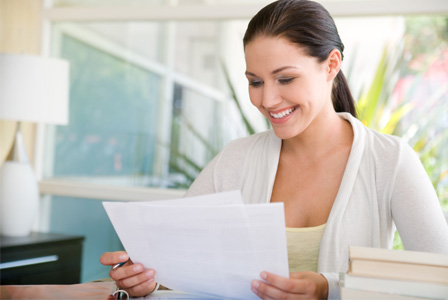 A Woman Smiling and Looking at a Piece of Paper